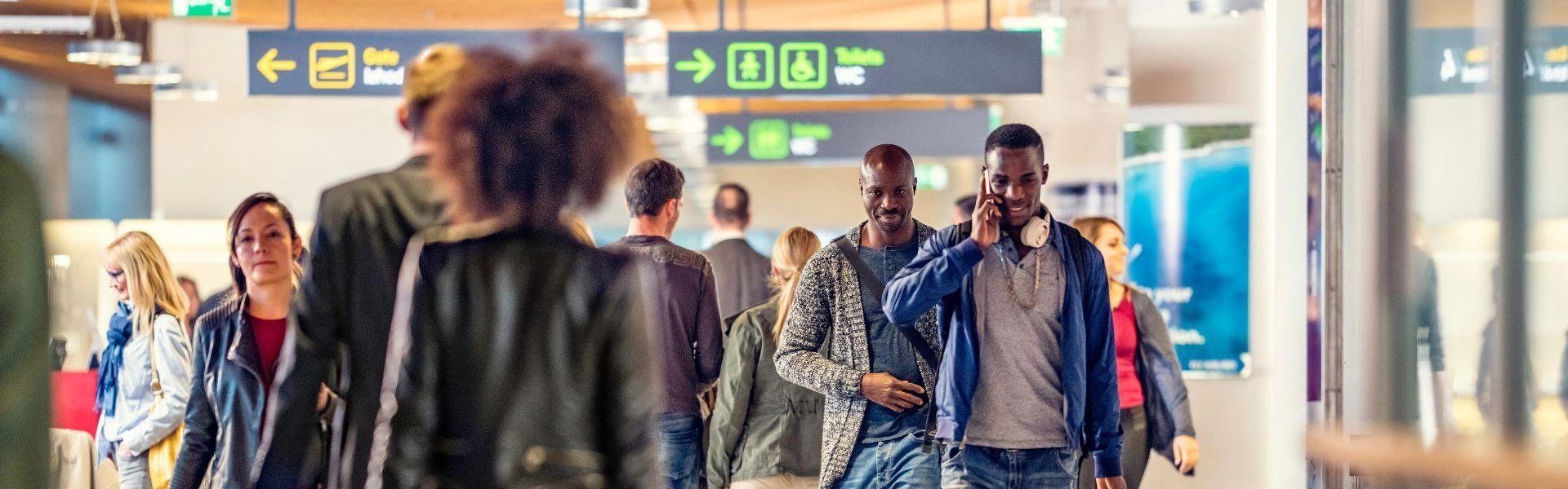 Grupo de pessoas caminhando pelo aeroporto segurando bagagem.