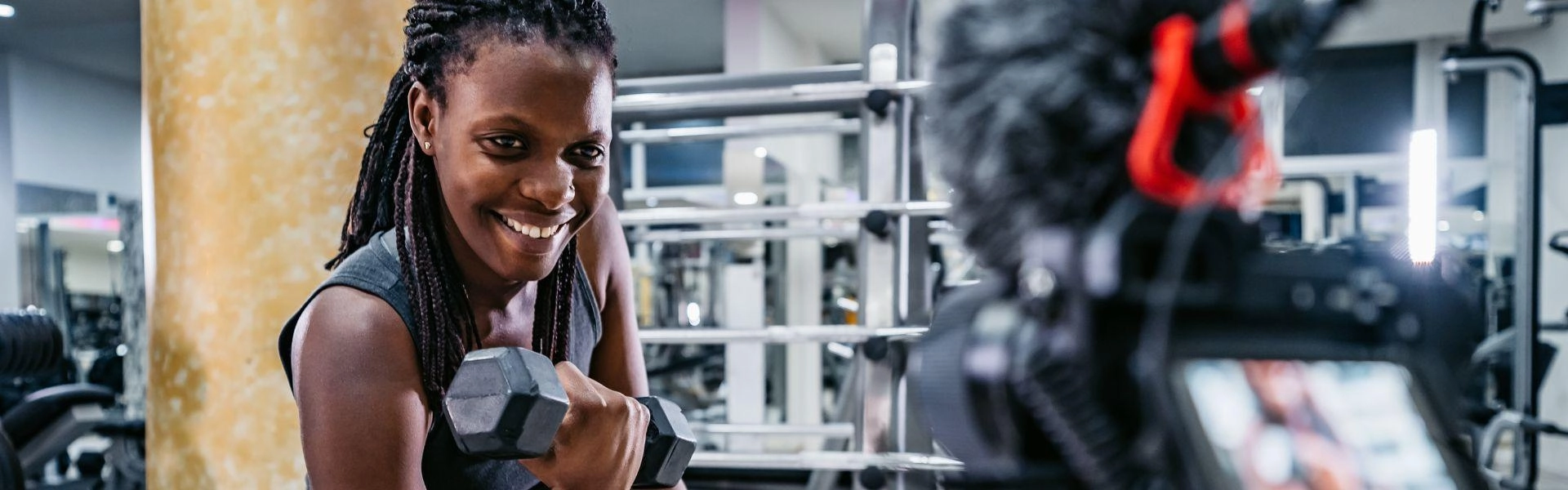 Influencier fitness gravando vídeo se exercitando na academia.