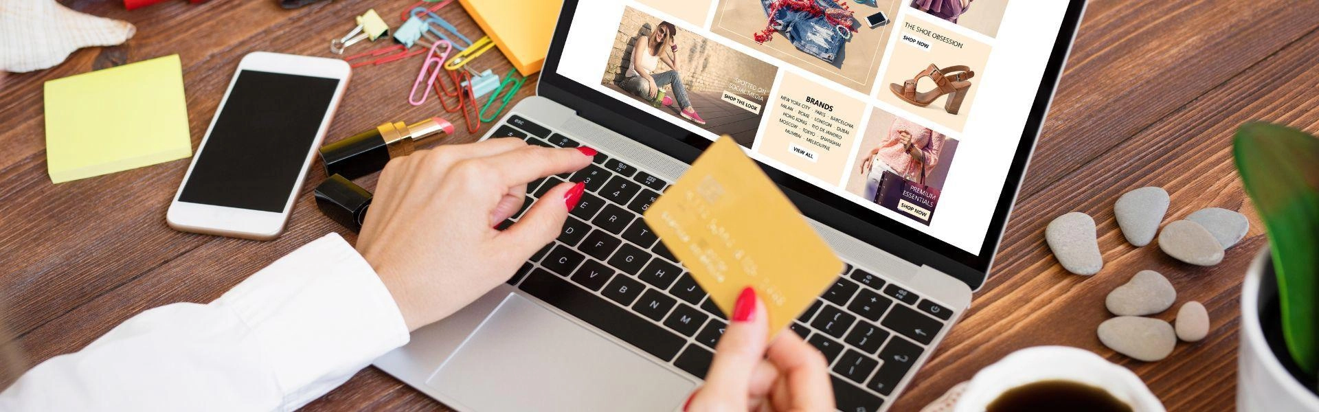 Uma pessoa realizando compras online no computador e segurando um cartão na mão.