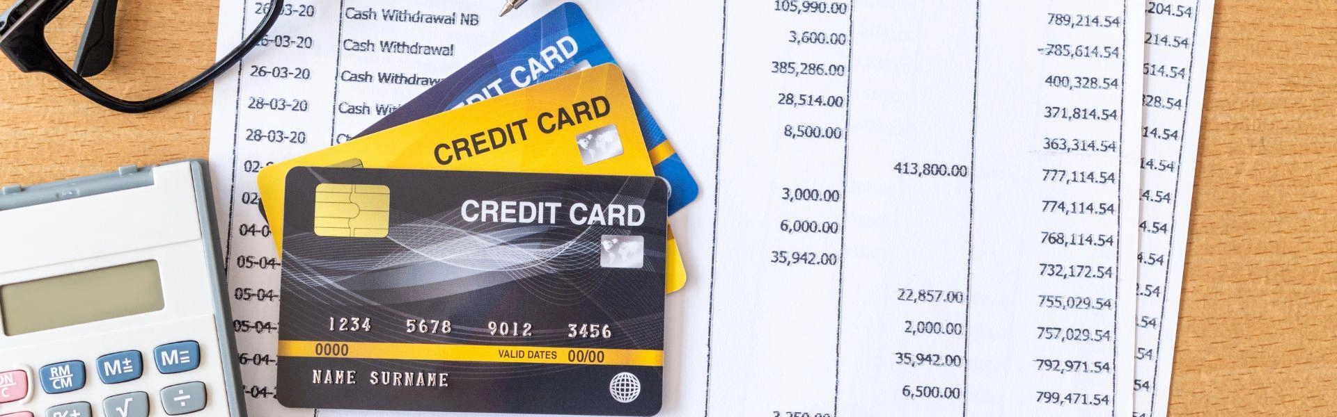 Calculadora, cartões de crédito e papéis com dívidas registradas.