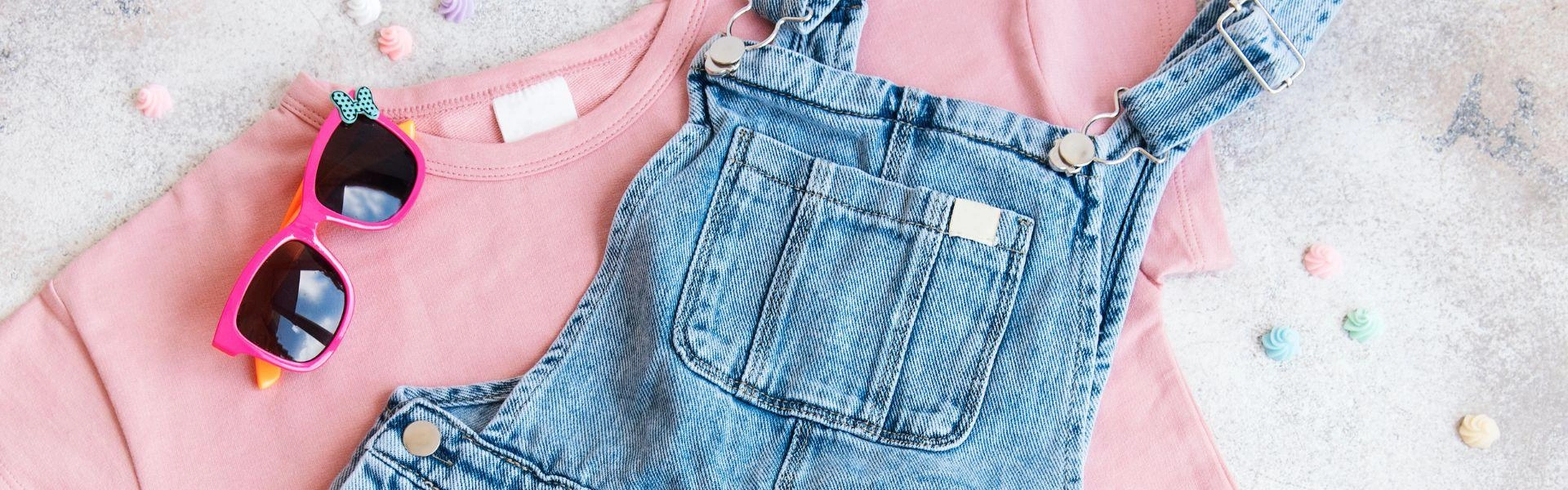 Roupas infantis: uma camisa rosa e jardineira jeans.