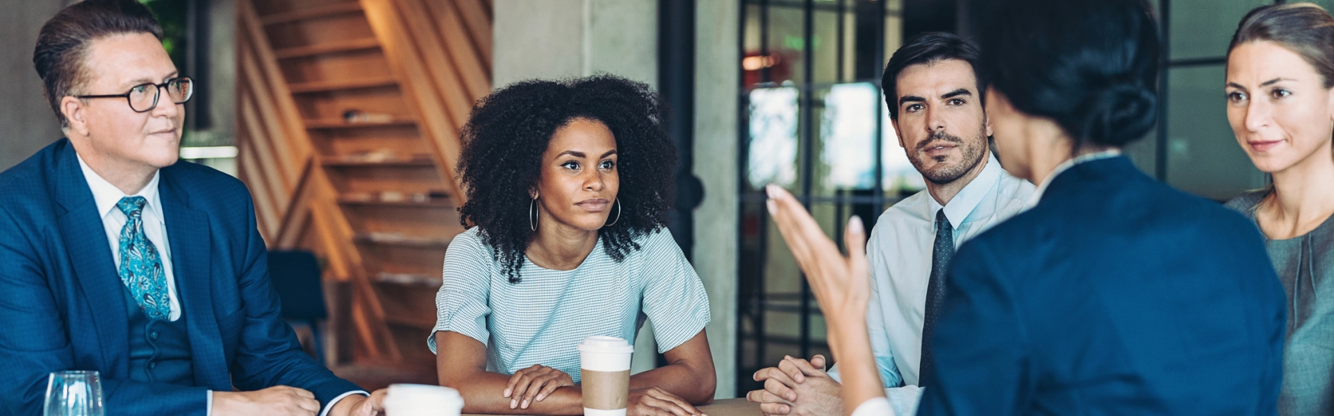 Grupo de cinco pessoas em reunião conversando sobre liderança.