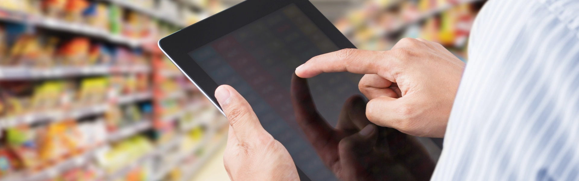 Mãos de um homem tocando a tela de um tablet em um mercado