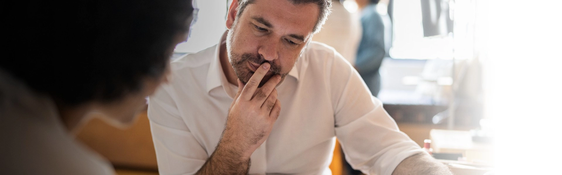 Homem branco com barba pensando enquanto lê.