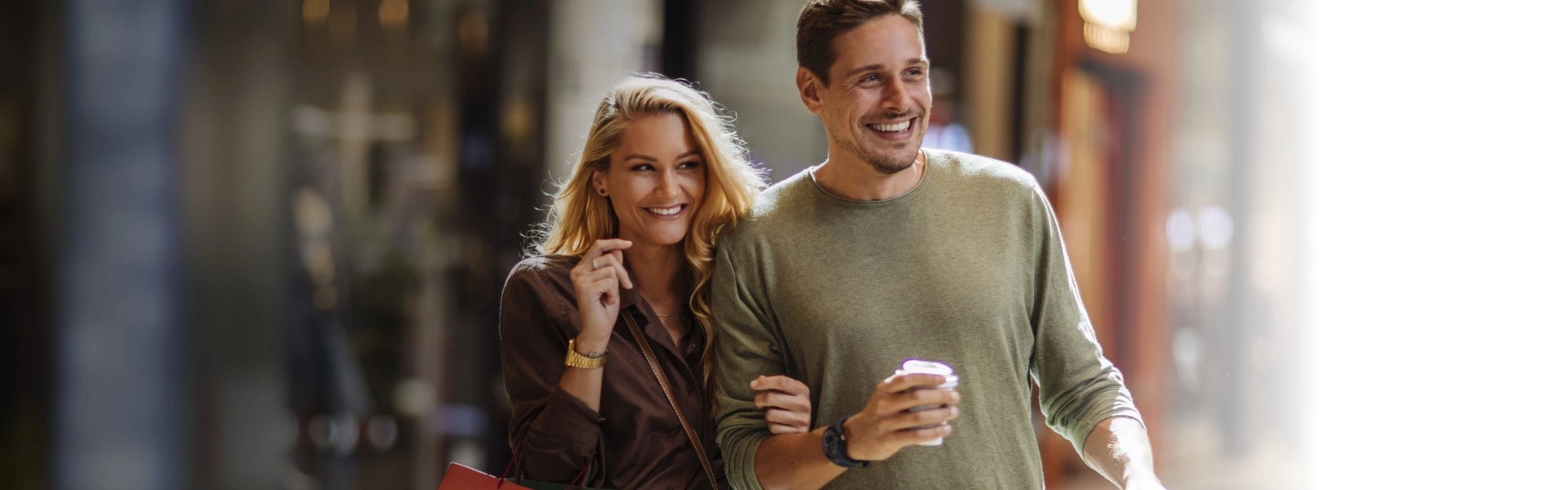 Casal de braços dados, sorrindo em um centro de compras