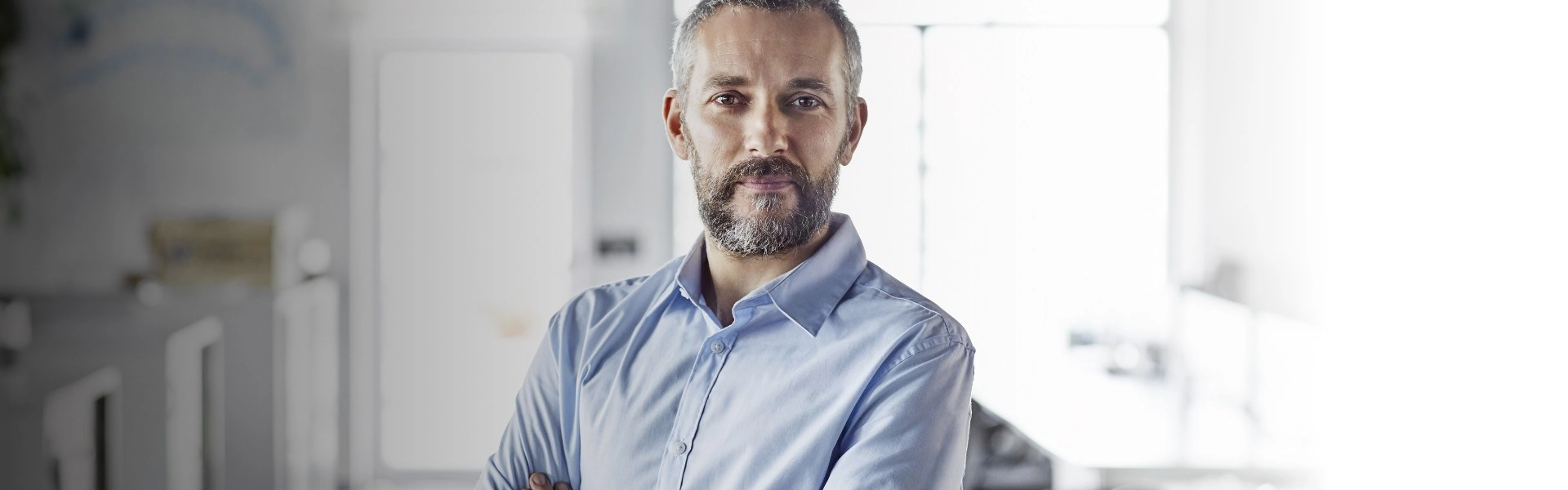 Homem branco de barba e cabelo grisalho com olhar otimista