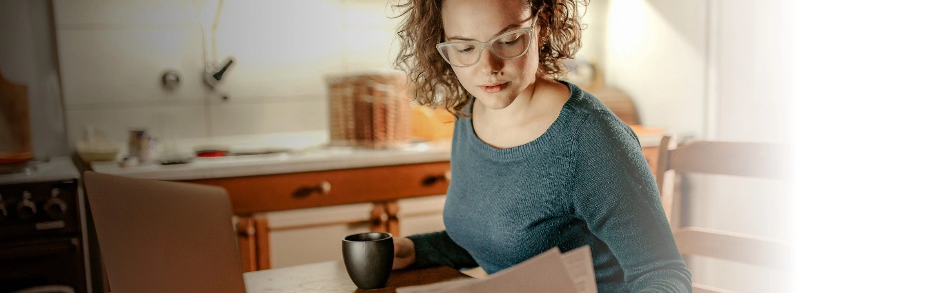 Mulher branca lendo papel com xícara na mão