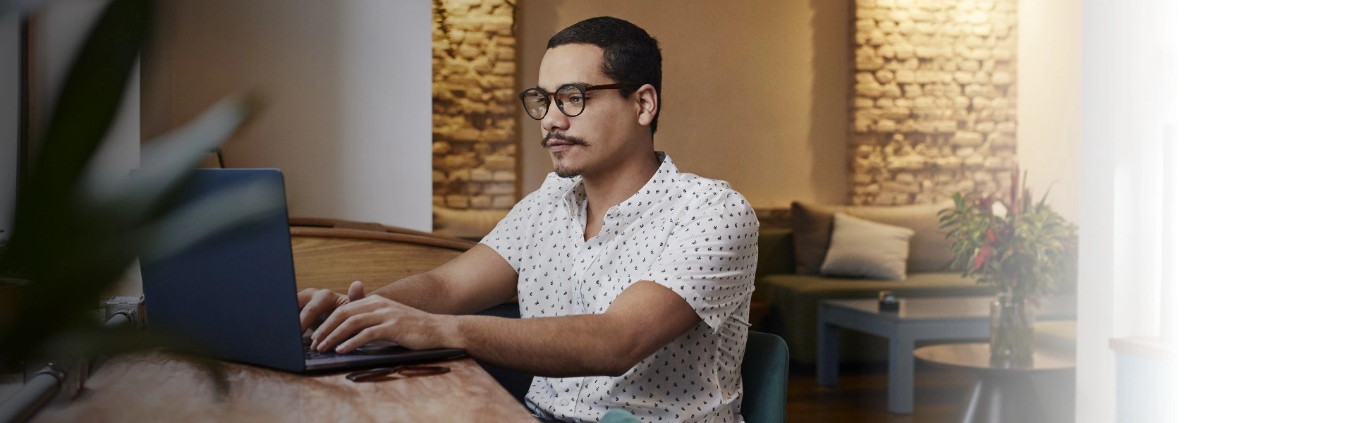 Homem de óculos concentrado em seu notebook