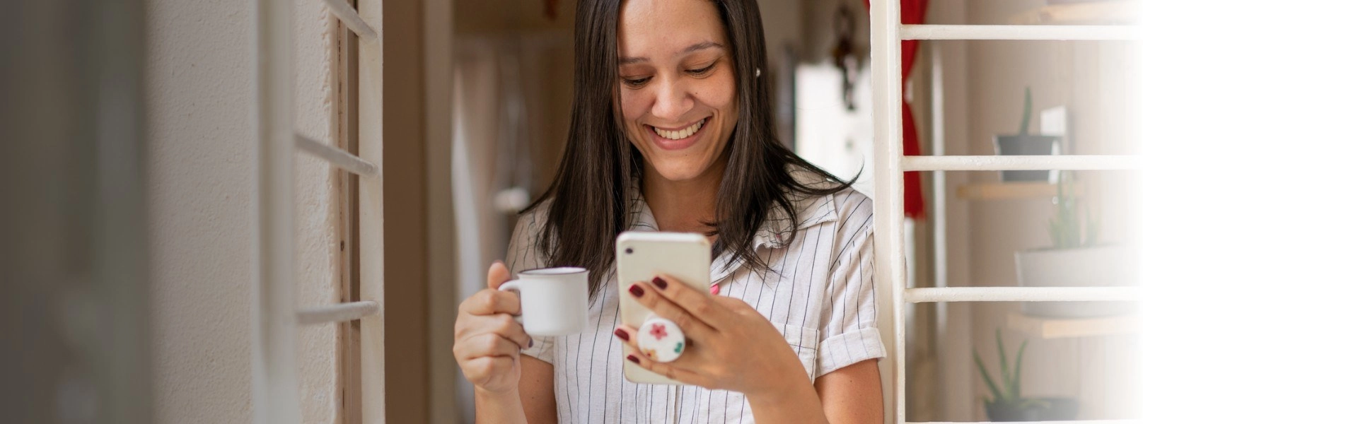 Mulher sorrindo enquanto olha para o celular e emite a Guia DAS