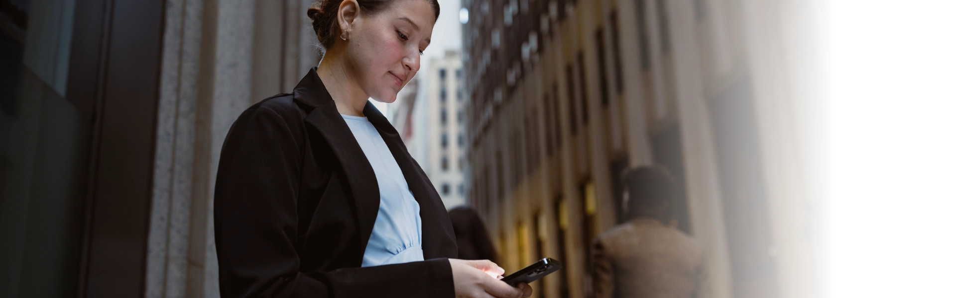 Mulher branca com roupa social a caminho da empresa confere notificações de seu celular