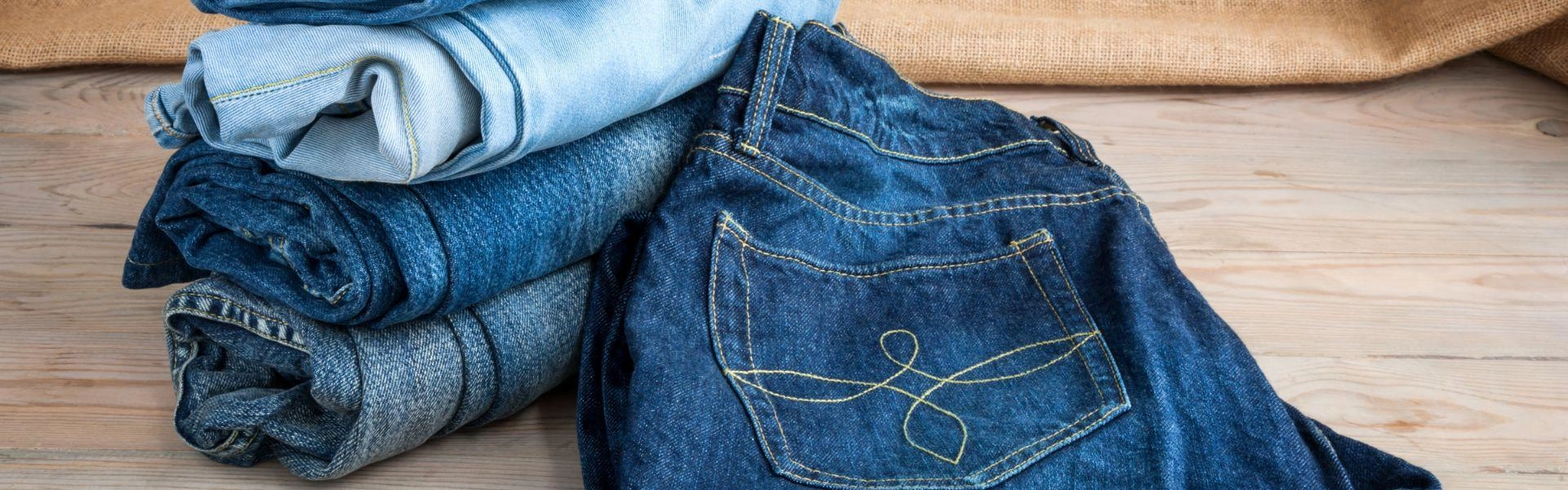 Calças jeans dobradas em cima de uma superfície plana e lisa.