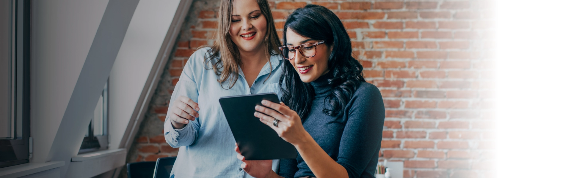 Duas mulheres brancas assistem webinar sobre transformação digital em tablet