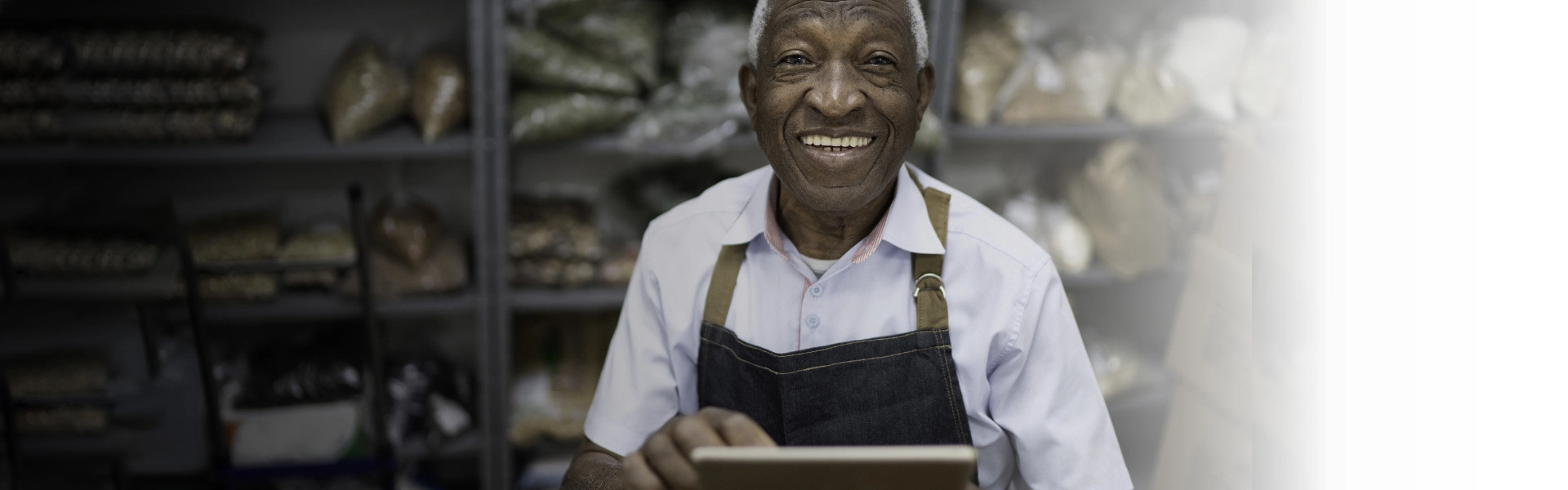 Homem negro sorrindo segurando um tablet.