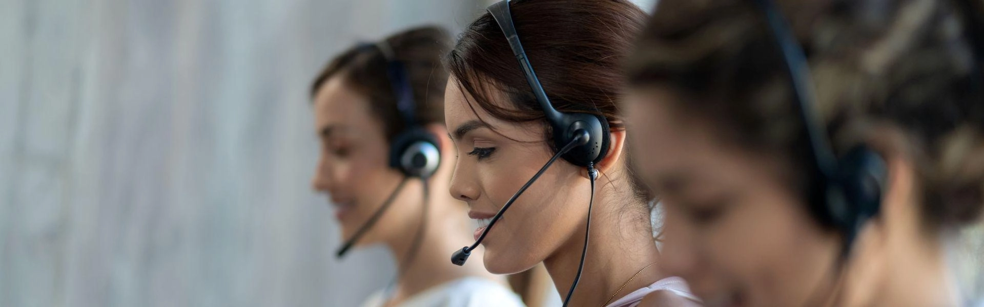 Três mulheres realizando atendimento ao consumidor por telefone.