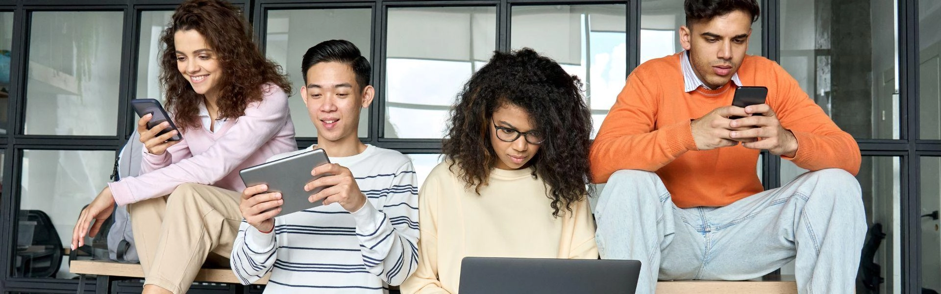 Jovens utilizando aparelhos celulares, laptops e tablets.
