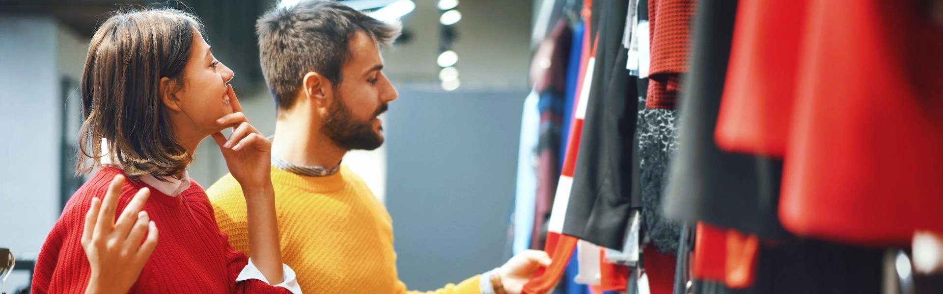 Uma mulher e um homem conferindo roupas em uma loja