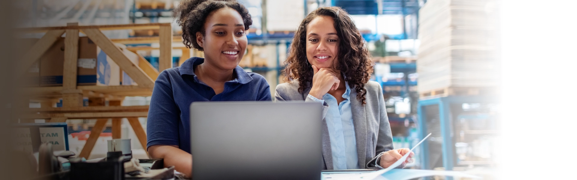 Duas mulheres negras navegam na internet por meio de notebook.