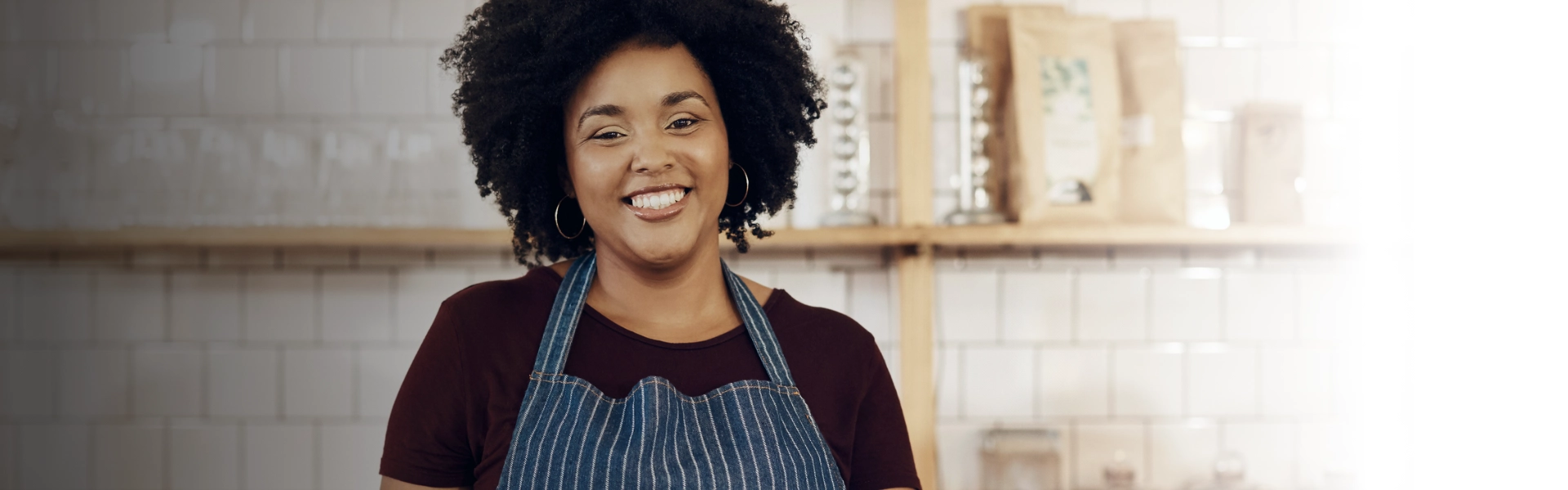 " Mulher negra com avental sorri para câmera."