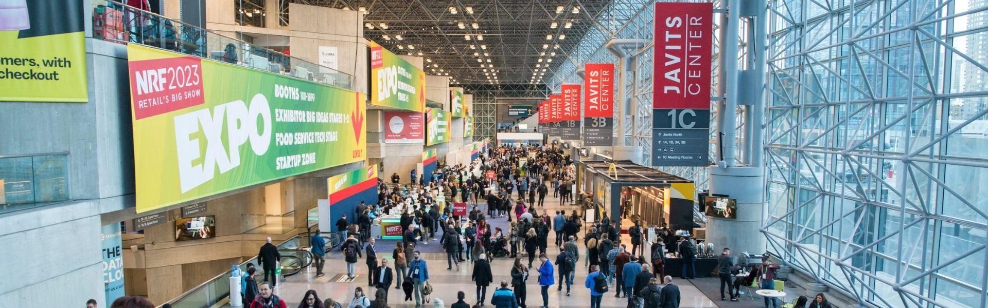 Evento NRF 2023: diversas pessoas em um corredor e outdoors.