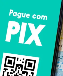 Na imagem temo um celular com "Pague com PIX" escrito na tela e ao lado dele, notas de reais.