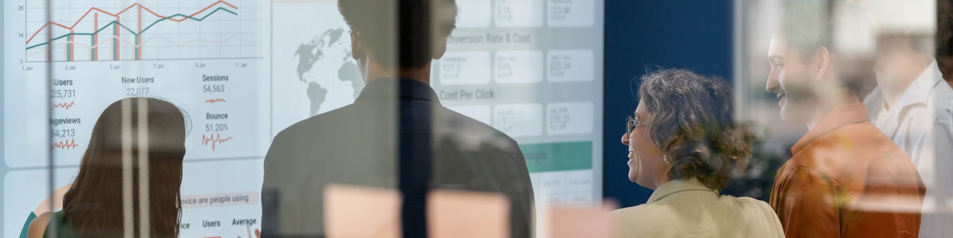 Grupo de profissionais analisando dashboards com gráficos e métricas de desempenho em uma tela grande, representando a tomada de decisão orientada por dados.
