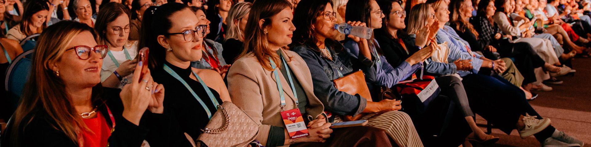 úblico formado majoritariamente por mulheres empreendedoras assistindo a palestras no Delas Summit, evento voltado à liderança e ao empreendedorismo feminino.