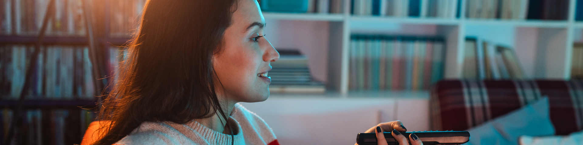 Mulher assistindo TV a noite em sala de estar moderna, ambiente aconchegante com livros e decoração elegante.