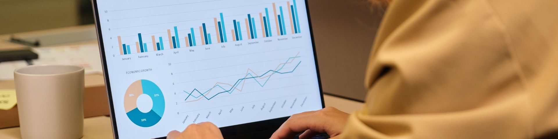 Mulher analisando gráficos e dados de negócios em um laptop, com foco em estratégias de mercado e crescimento empresarial.