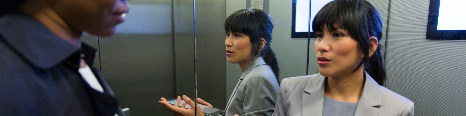 Empreendedora apresenta suas ideias em uma conversa rápida dentro de um elevador, simbolizando o chamado “elevator pitch”, recurso essencial para brilhar em feiras e eventos de negócios.