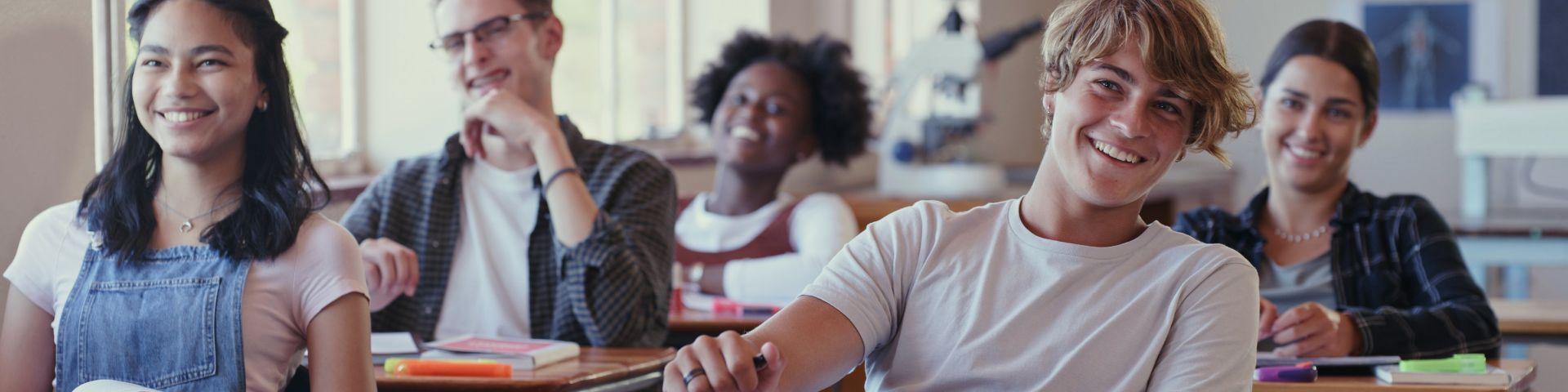 Grupo de estudantes sorrindo e participando de aula em sala de aula moderna, aprendendo e interagindo com entusiasmo.