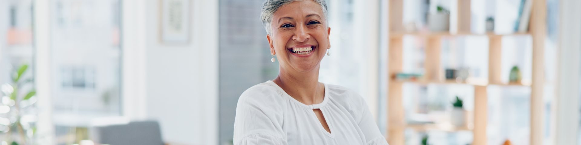 Mulher idosa sorridente em ambiente de escritório, transmitindo alegria e bem-estar, promovendo positividade e saúde mental.