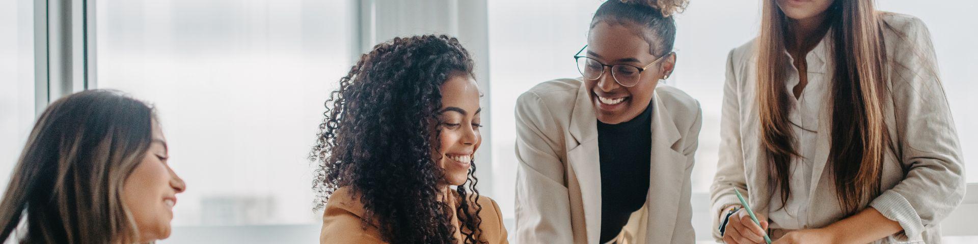 Grupo de pessoas em uma reunião de negócios, sorrindo e interagindo em ambiente de escritório moderno, promovendo networking e trabalho em equipe.