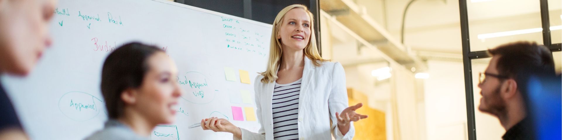 Mentora de negócios apresentando estratégias de escalabilidade para um grupo de empreendedores em sala de reunião, destacando práticas de gestão e planejamento essenciais para startups.