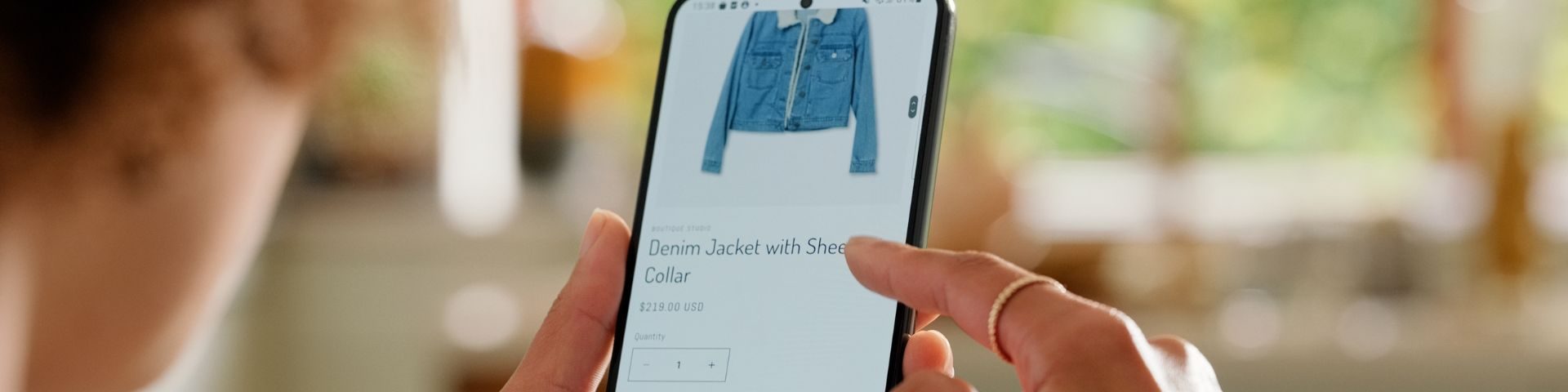Pessoa navega em loja virtual pelo celular, analisando página de produto e preço, representando a experiência de compra em um site de vendas.